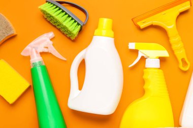 Turuncu arka planda farklı temizlik malzemeleri