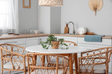 Mutfağın içinde yemek masası ve beyaz tezgahlar var.