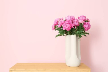 Renk duvarının yanındaki raflarda duran pembe şakayık vazosu.