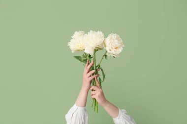 Yeşil arka planda beyaz şakayıklı kadın elleri