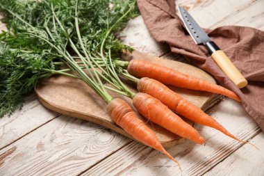 Hafif ahşap arka planda yaprakları olan taze havuçlar.