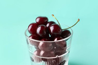 Mavi arka planda tatlı kirazlı bardak
