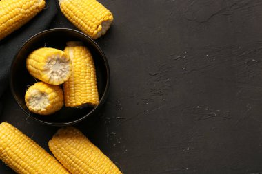 Siyah arka planda kesilmiş taze mısır koçanları ile kase