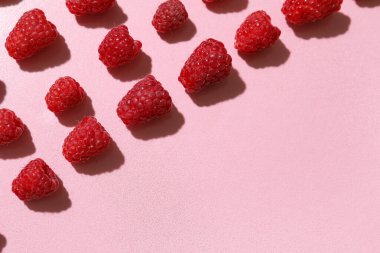 Pembe arka planda bir sürü taze ahududu