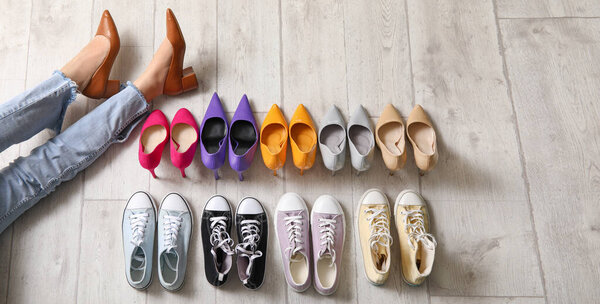 Female legs with different stylish shoes on floor, top view
