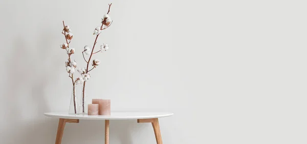 光の壁の近くに綿の花や香りのろうそくとスタイリッシュなテーブル デザインのバナー — ストック写真