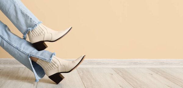 Женские ноги в стильной кожаной обуви возле бежевой стены. Баннер для дизайна