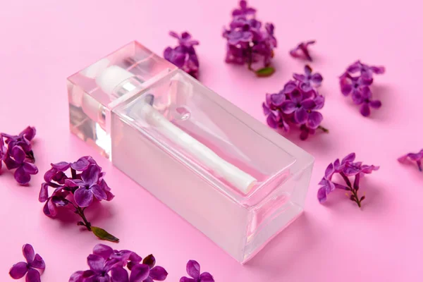 Beautiful lilac flowers and bottle of perfume on pink background, closeup