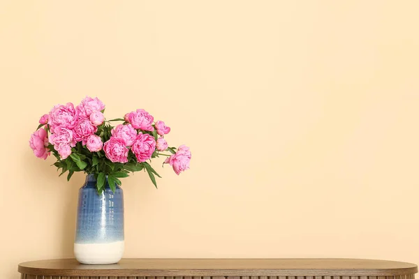 Vase of pink peonies on dresser near beige wall