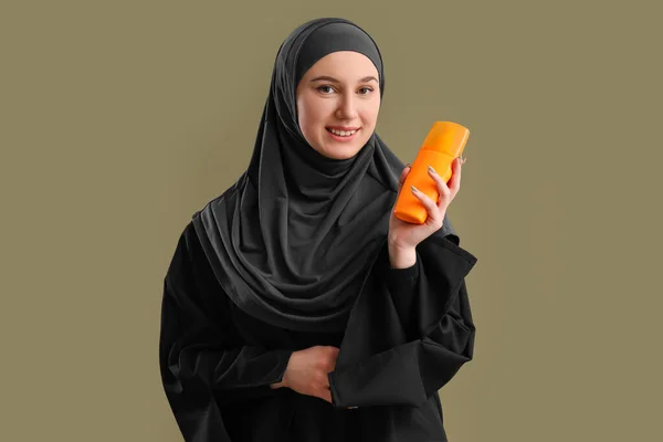 緑の背景に日焼け止めクリームと若いイスラム教徒の女性 — ストック写真