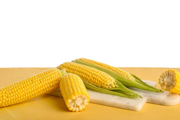 Deska Świeżymi Kolbami Kukurydzy Żółtym Stole Białym Tle — Zdjęcie stockowe