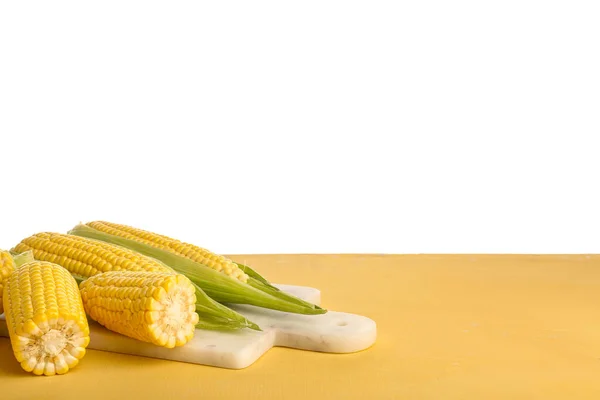 Deska Świeżymi Kolbami Kukurydzy Żółtym Stole Białym Tle — Zdjęcie stockowe