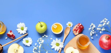 Olgun narlar, elmalar, çiçekler ve mavi arka planda bal. Rosh Hashanah (Yahudi Yeni Yılı) kutlaması