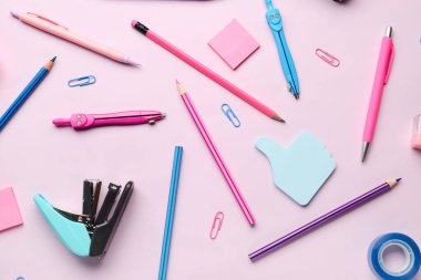 Pembe arka planda kırtasiye malzemeleriyle kompozisyon