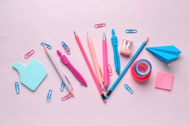 Pembe arka planda kırtasiye malzemeleriyle kompozisyon