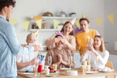 Genç adam partideki arkadaşına doğum günü pastası getiriyor.