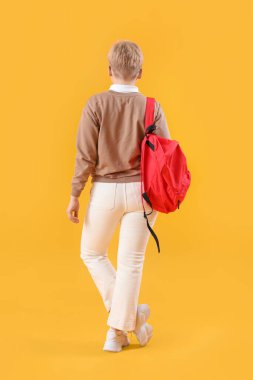 Sarı arka planda sırt çantalı bayan öğrenci.