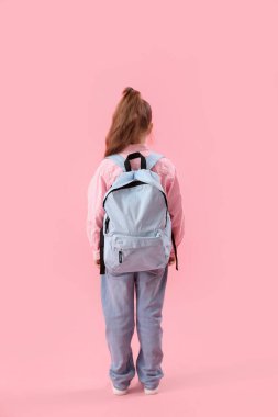 Pembe arka planda sırt çantası olan küçük okul kızı.