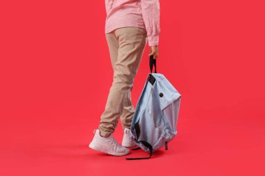 Kırmızı arka planda sırt çantası olan küçük Afro-Amerikalı öğrenci.