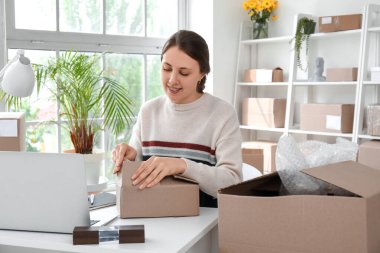 Ofisteki müşteri için paket hazırlayan genç bir kadın.