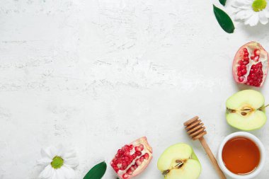 Taze meyveli kompozisyon, bir kase bal ve arka planda çiçekler. Rosh hashanah (Yahudi Yeni Yılı) kutlaması