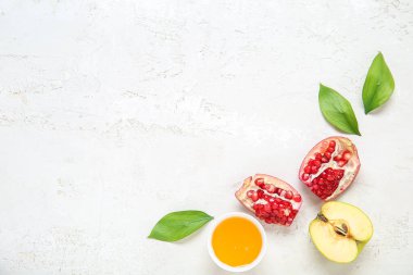 Arkaplanda olgun nar, elma, bal ve bitki yapraklarıyla kompozisyon. Rosh hashanah (Yahudi Yeni Yılı) kutlaması