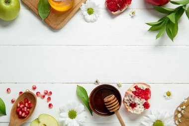 Hafif ahşap zemin üzerinde taze meyve, çiçek ve bal içeren kompozisyon. Rosh hashanah (Yahudi Yeni Yılı) kutlaması