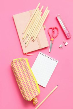 Pembe arka planda not defterleri ve okul kırtasiyesi