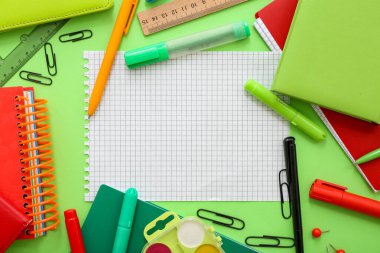 Yeşil arkaplanda boş defter bulunan farklı kırtasiyeden yapılmış çerçeve