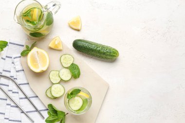 Beyaz arka planda salatalıklı bir sürahi limonata.