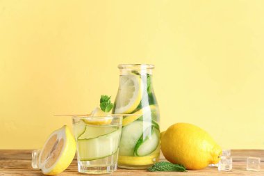 Ahşap masada salatalık ve bir şişe limonata.