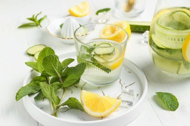 Beyaz arka planda salatalıklı bir sürahi limonata.