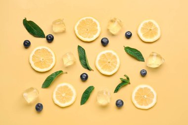 Buzlu limon dilimleri, turuncu arka planda nane ve yaban mersini.