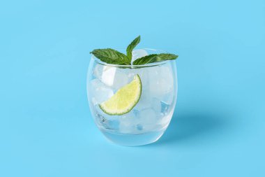Bir bardak limon dilimli buz ve mavi arka planda nane şekeri.