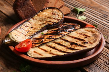 Ahşap arka planda leziz ızgara patlıcan ve domates tabağı, yakın plan.