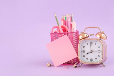 Leylak arka planında farklı kırtasiye malzemesi olan çalar saat