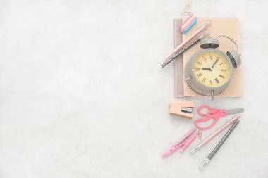 Bej arkaplanda farklı kırtasiye malzemesi olan çalar saat