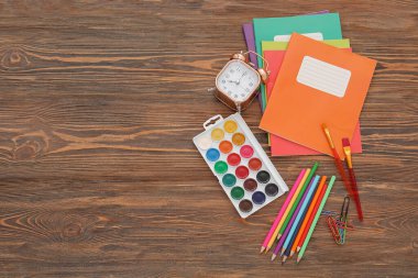 Kahverengi ahşap zemin üzerinde farklı kırtasiye malzemesi olan çalar saat