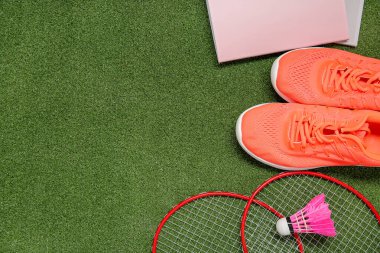 Raketli spor ayakkabılar, badminton servis aleti ve renkli arka planda kırtasiye malzemeleri.