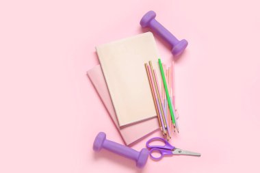 Dambıllar ve pembe arka planda farklı kırtasiye malzemeleri.