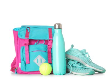 Spor ayakkabılı sırt çantası, tenis topu ve beyaz arka planda izole edilmiş bir şişe su.
