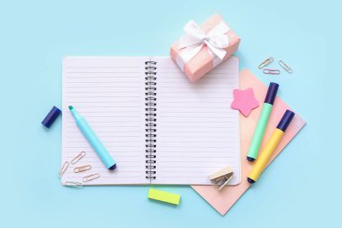Hediye kutusu ve mavi arkaplanda farklı kırtasiyeli defterler