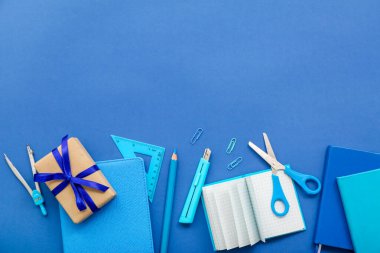 Mavi zemin üzerinde farklı kırtasiye malzemesi olan hediye kutusu