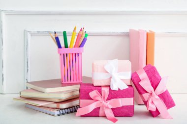 Kitaplı hediye kutuları ve beyaz masada farklı kırtasiye malzemeleri.