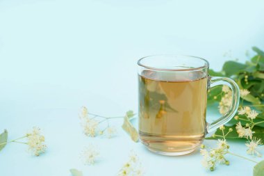 Mavi arka planda bir bardak ıhlamur çayı.