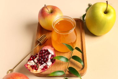 Bej arka planda, Rosh Hashanah kutlaması (Yahudi Yeni Yılı) için bal, nar ve elma dolu tahta tahta tahta tabela