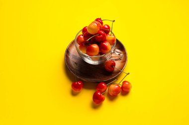 Sarı arka planda tatlı kirazlı cam bardak.