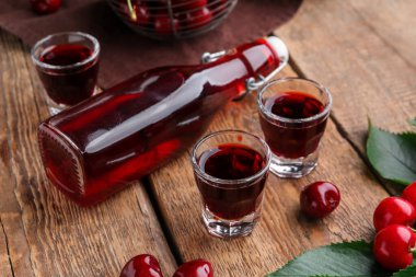 Ahşap zemin üzerinde kiraz likörü olan shot ve şişe.