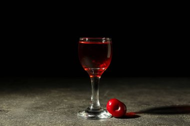 Siyah arka planda vişne likörlü bir bardak.