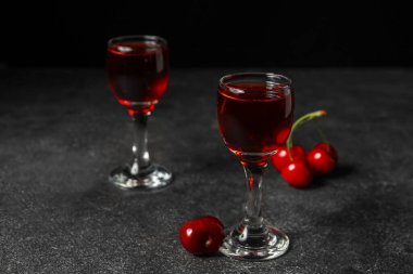 Siyah zemin üzerinde vişne likörü olan bardaklar.